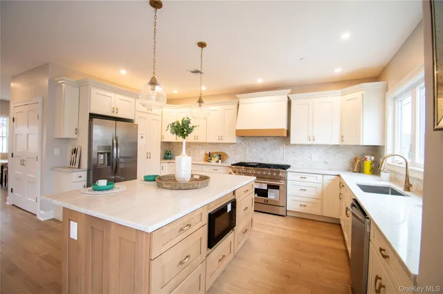a large kitchen with a large counter top a sink stainless steel appliances and cabinets