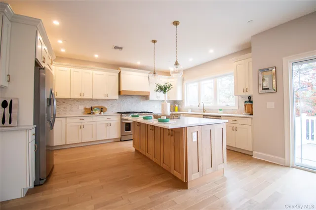 a large kitchen with white cabinets and wooden floor