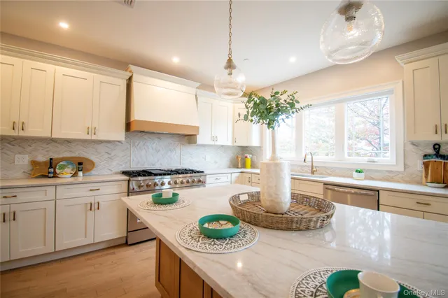 a large kitchen with kitchen island granite countertop a stove a sink a center island and furniture