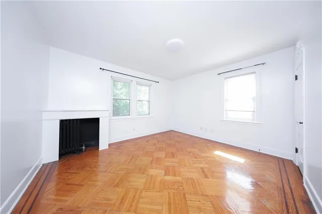 an empty room with windows and fireplace