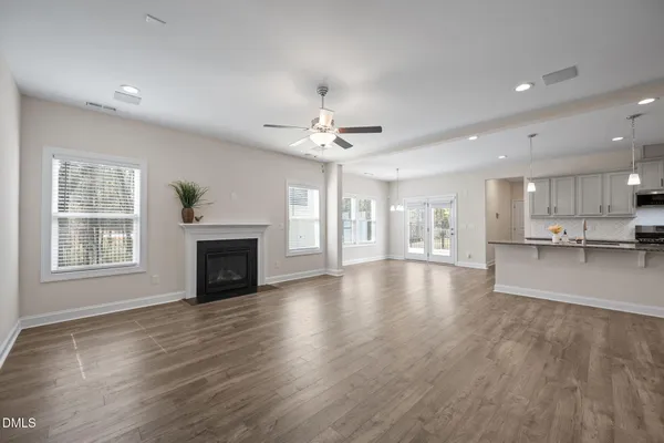 a view of an empty room with wooden floor and a ceiling fan
