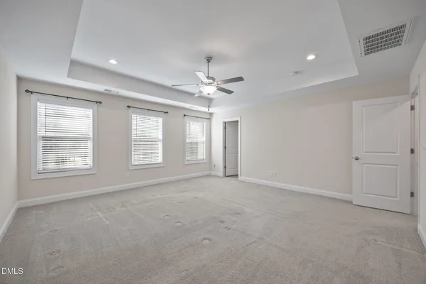 an empty room with chandelier fan and windows