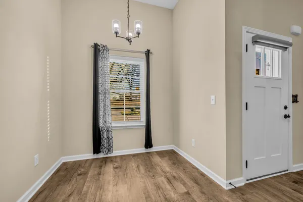 an empty room with wooden floor cabinet and windows