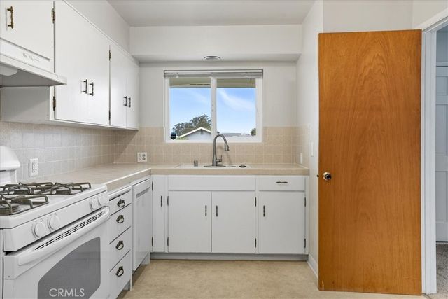 a kitchen with white cabinets and sink