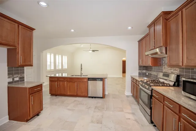 a large kitchen with stainless steel appliances granite countertop a stove a sink dishwasher and a refrigerator