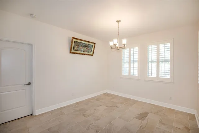 an empty room with chandelier fan and windows