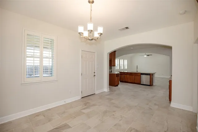 a view of an empty room with chandelier fan and windows