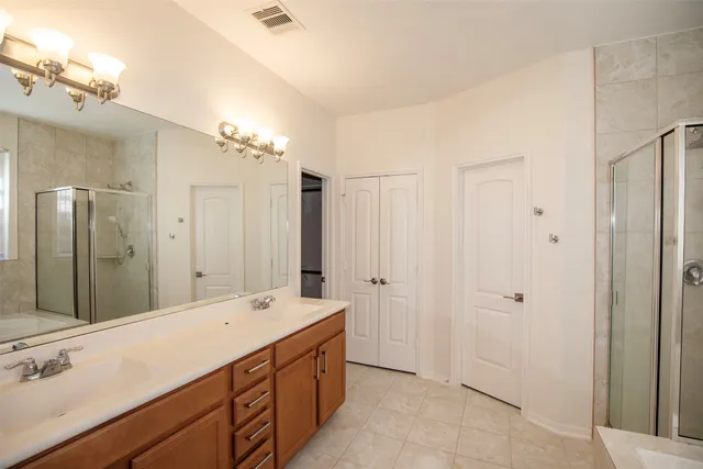 a spacious bathroom with a double vanity sink a large mirror and shower