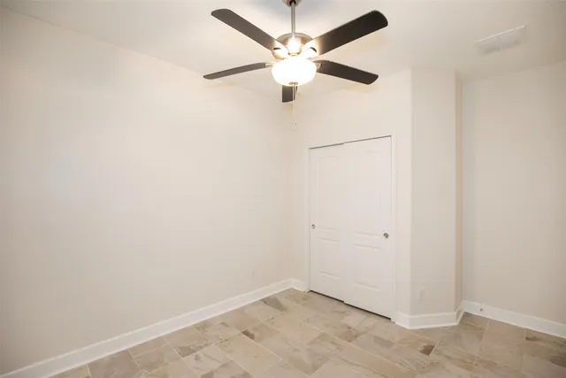 an empty room with a ceiling fan and a window