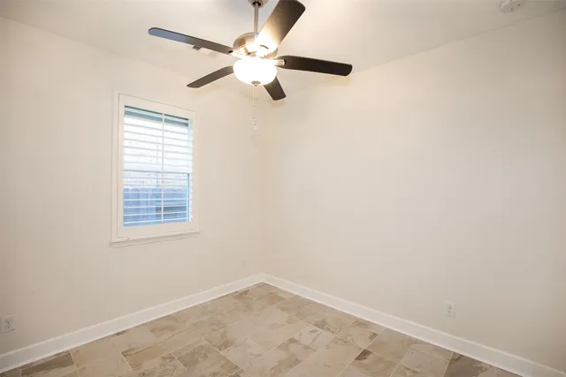 an empty room with a window and a fan