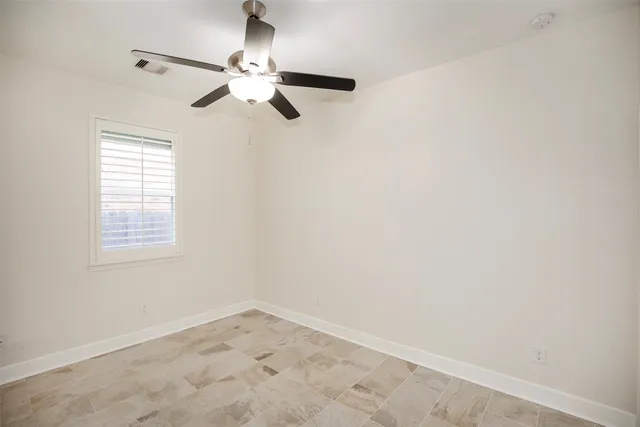 an empty room with a window and a fan