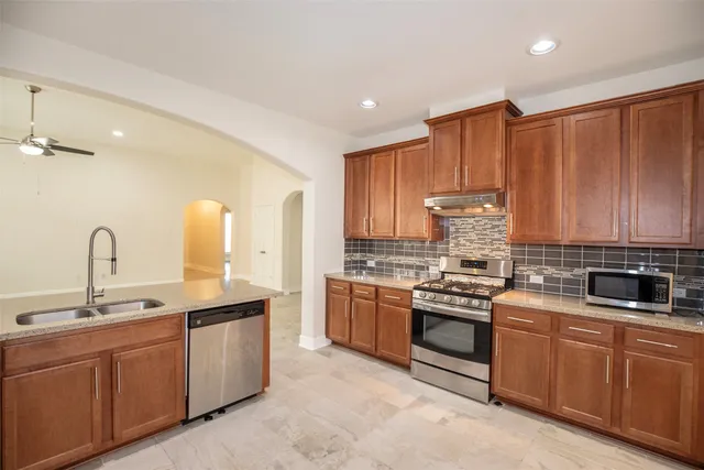 a kitchen with kitchen island granite countertop a sink stainless steel appliances and cabinets