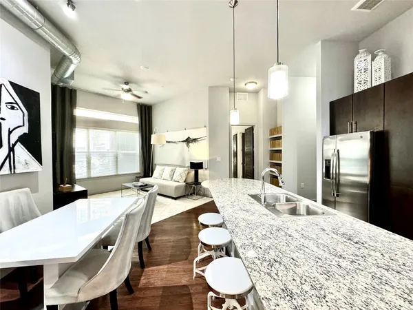 a large kitchen with granite countertop a stove a sink a dining table and chairs