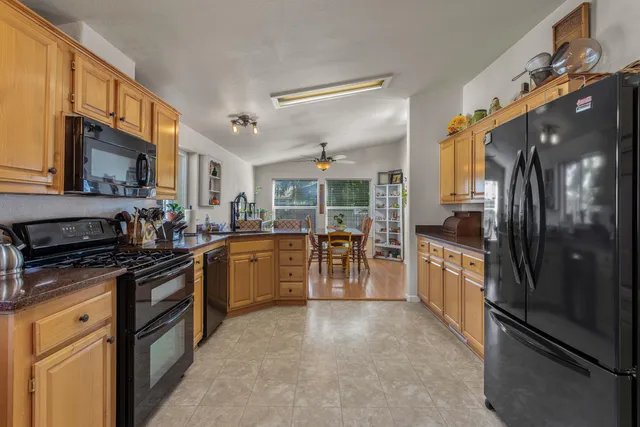 a kitchen with stainless steel appliances granite countertop a refrigerator a stove and a sink