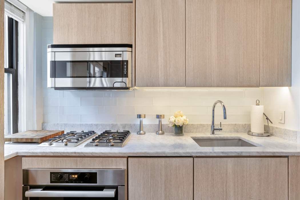 333 East 53rd Street, Unit 5B Manhattan, NY 10022 - Photo 4 of 12 a kitchen with granite countertop a stove and a sink