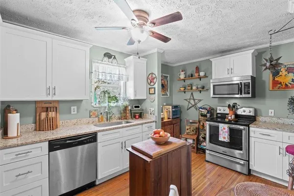 a kitchen with stainless steel appliances granite countertop a sink a stove and cabinets
