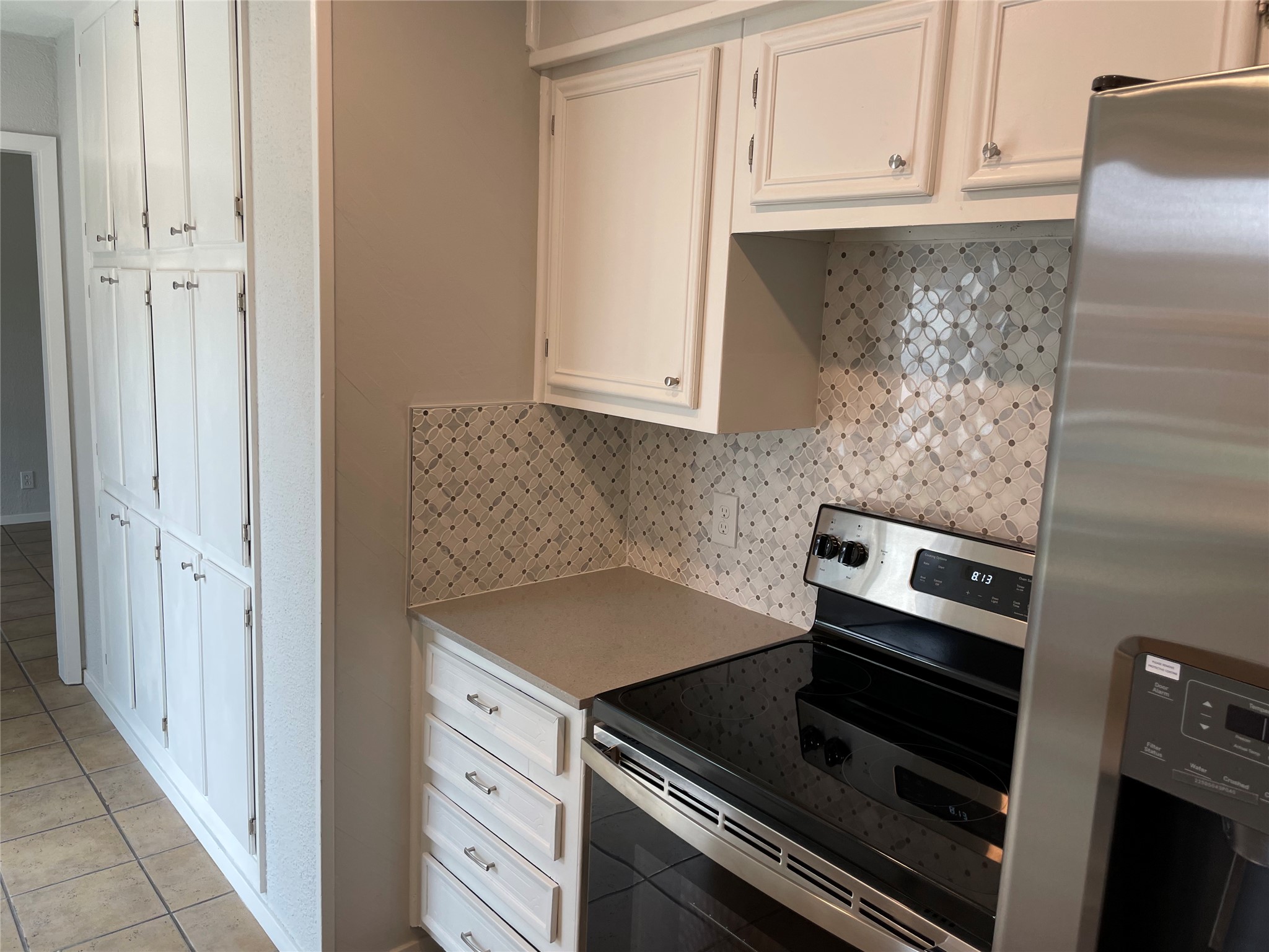 4619 Jinx Avenue, Unit A Austin, TX 78745 - Photo 8 of 21 Kitchen featuring white cabinetry, patterned tile backsplash, stainless steel range, and tile flooring