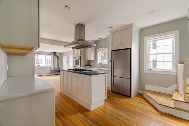 a kitchen with stainless steel appliances a refrigerator a sink dishwasher a stove and white cabinets with wooden floor