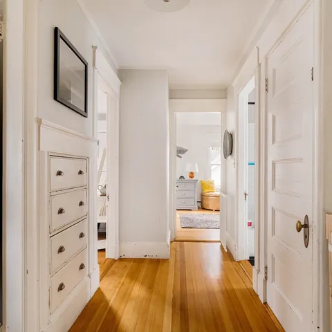 a view of a hallway with wooden floor and furniture