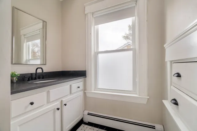 a bathroom with a granite countertop sink mirror vanity and next to a window