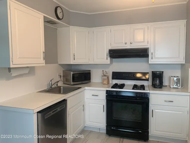 a kitchen with white cabinets and appliances