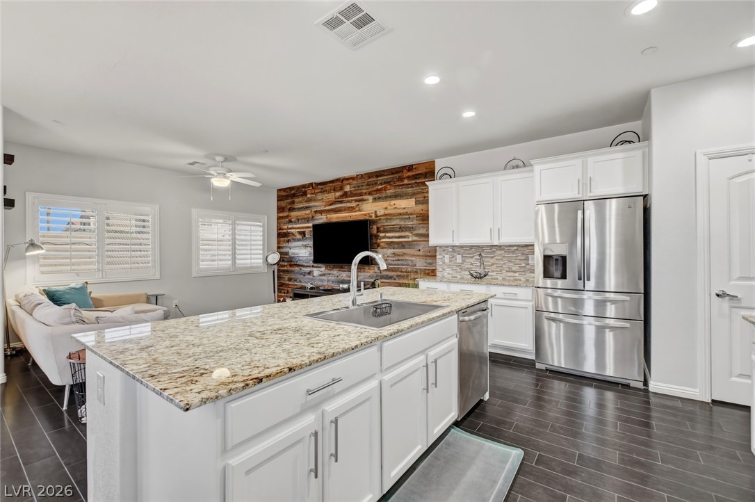 48 Jasmine Point Street Henderson, NV 89074 - Photo 25 of 62 A chef's kitchen boasts granite counters, stainless steel appliances, and a unique wood-paneled accent wall.