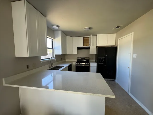 a kitchen with a refrigerator a sink a stove a microwave a counter top space and cabinets