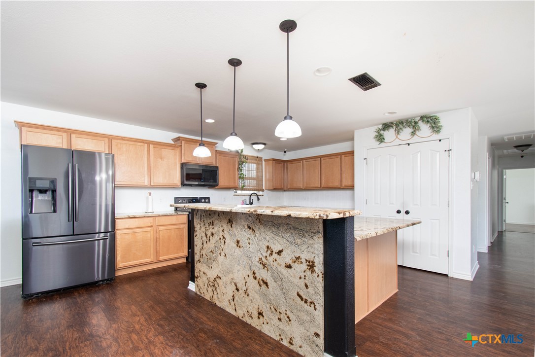 519 Pleasant View Road Troy, TX 76579 - Photo 6 of 30 a kitchen with stainless steel appliances kitchen island granite countertop a refrigerator a sink and wooden floor