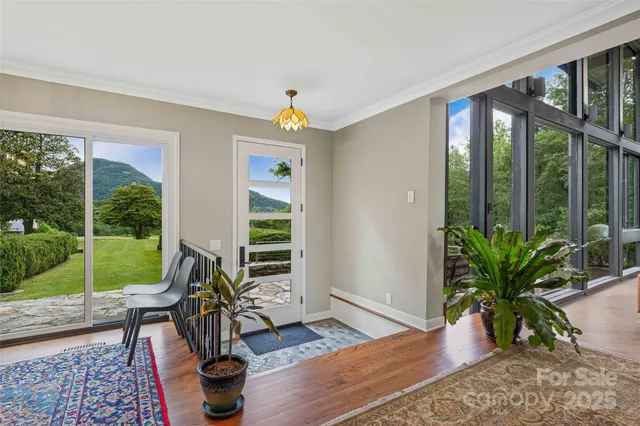 a living room with furniture large windows and wooden floor