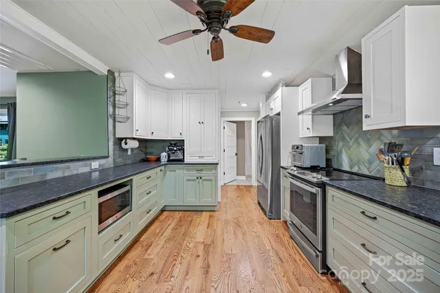 a large kitchen with stainless steel appliances granite countertop a lot of counter space and wooden floors