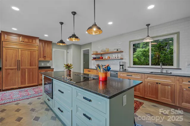 a kitchen with stainless steel appliances granite countertop a sink a stove and a wooden cabinets