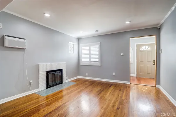an empty room with wooden floor fireplace and windows