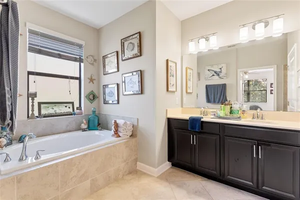 a spacious bathroom with a tub double sink window and mirror