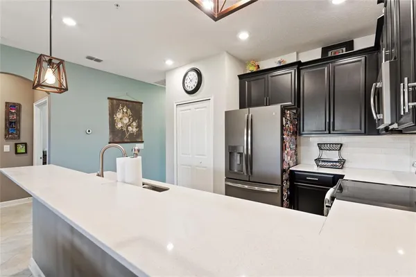a kitchen with stainless steel appliances kitchen island granite countertop a refrigerator and a sink