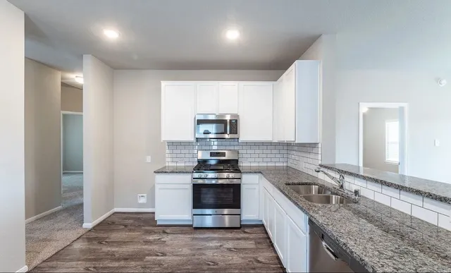 a kitchen with stainless steel appliances granite countertop a stove a sink and a refrigerator