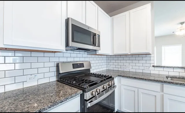 a kitchen with granite countertop a stove sink and microwave