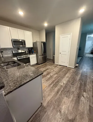 a kitchen with stainless steel appliances granite countertop a sink a stove and a refrigerator