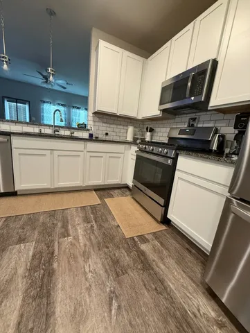 a kitchen with stainless steel appliances granite countertop a stove a sink and a microwave