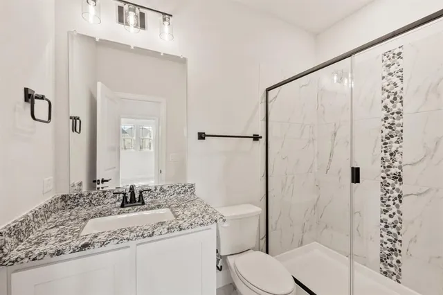 a bathroom with a granite countertop sink toilet and shower