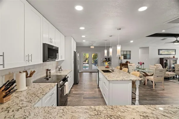 a large kitchen with stainless steel appliances kitchen island granite countertop a large counter top a stove a sink a dining table and chairs