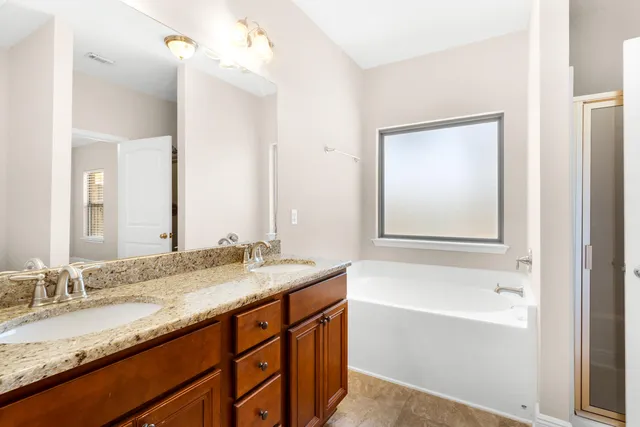 a bathroom with a granite countertop bathtub sink double vanity and mirror