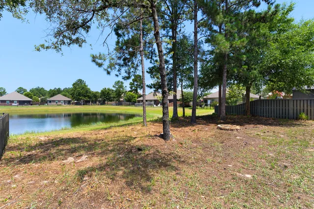 a view of a lake with a yard and large trees