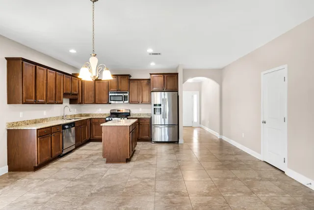 a large kitchen with a large counter top a sink a stove a refrigerator and a window