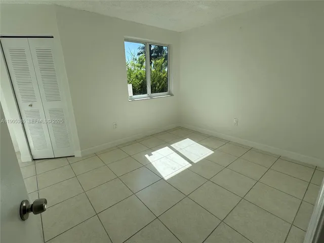 a view of an empty room with closet and a window