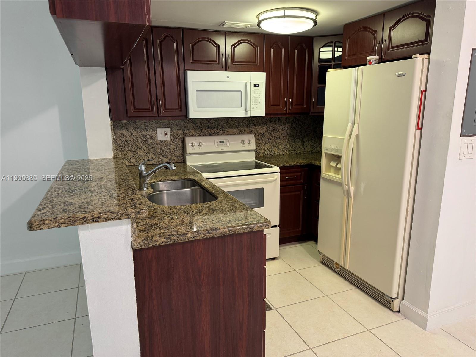 8585 Northwest 6th Lane, Unit 9208 Miami, FL 33126 - Photo 4 of 22 a kitchen with granite countertop a refrigerator and a sink