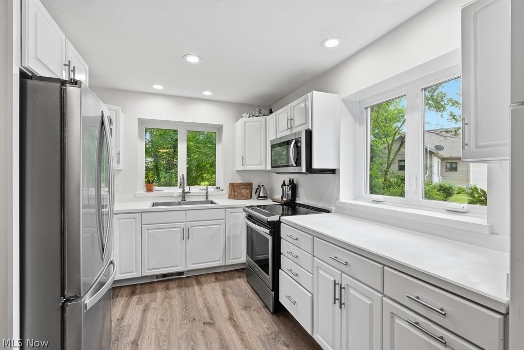 2323 Call Road Stow, OH 44224 - Photo 19 of 42 Modern kitchen featuring white cabinetry, light-toned countertops, stainless steel appliances, wood-finish flooring, and recessed lighting