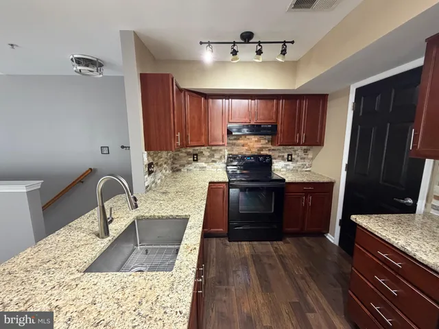 a kitchen with kitchen island granite countertop a sink stove and refrigerator