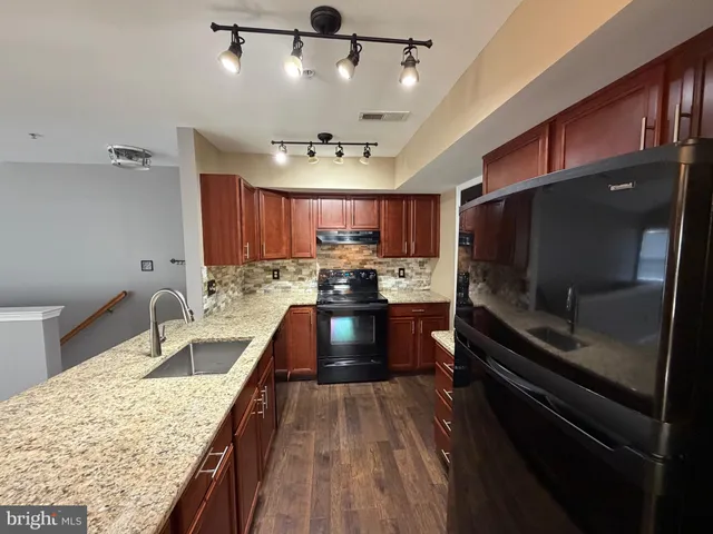 a kitchen with stainless steel appliances kitchen island granite countertop a sink stove and refrigerator