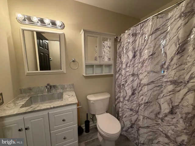 a bathroom with a granite countertop toilet sink and mirror