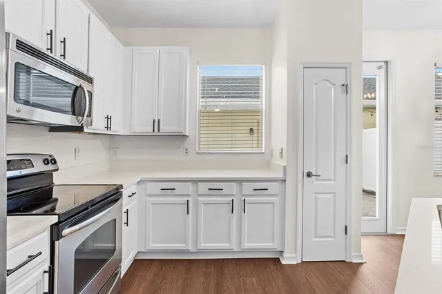 a kitchen with granite countertop white cabinets and stainless steel appliances